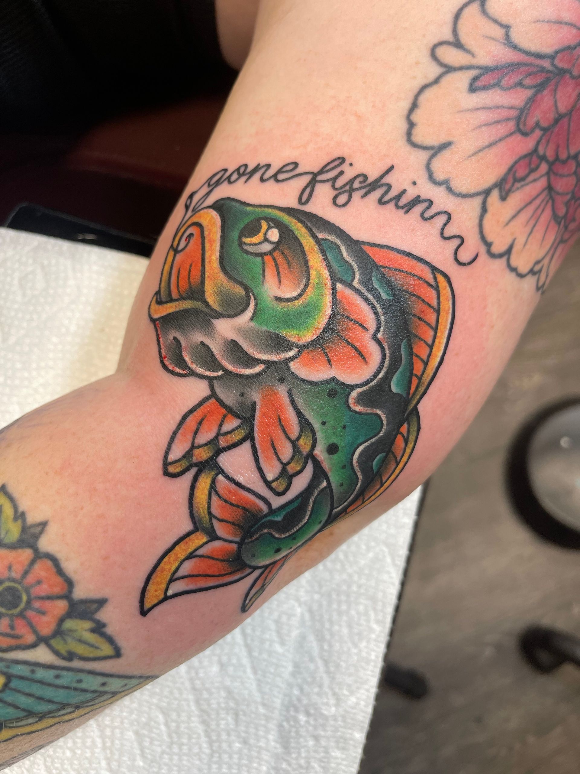A tattoo of a fish with the words gone fishing below it