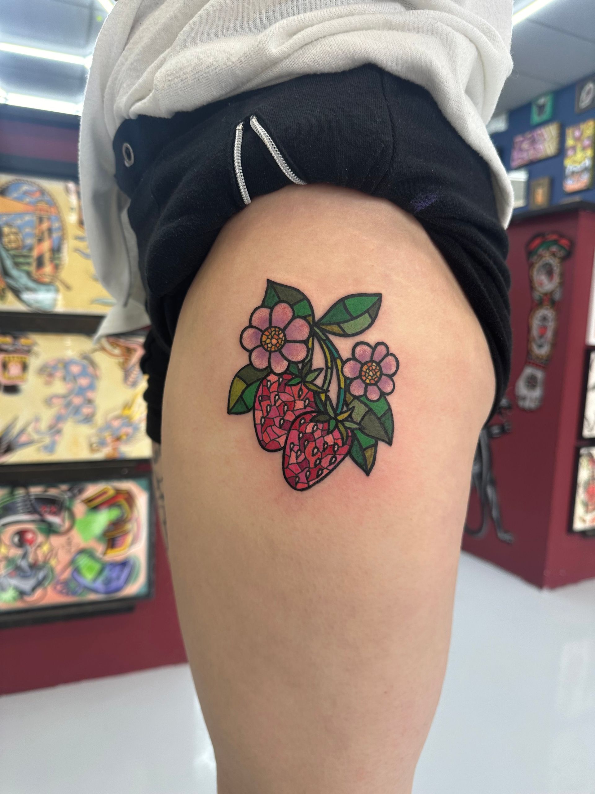 A woman has a strawberry tattoo on her thigh