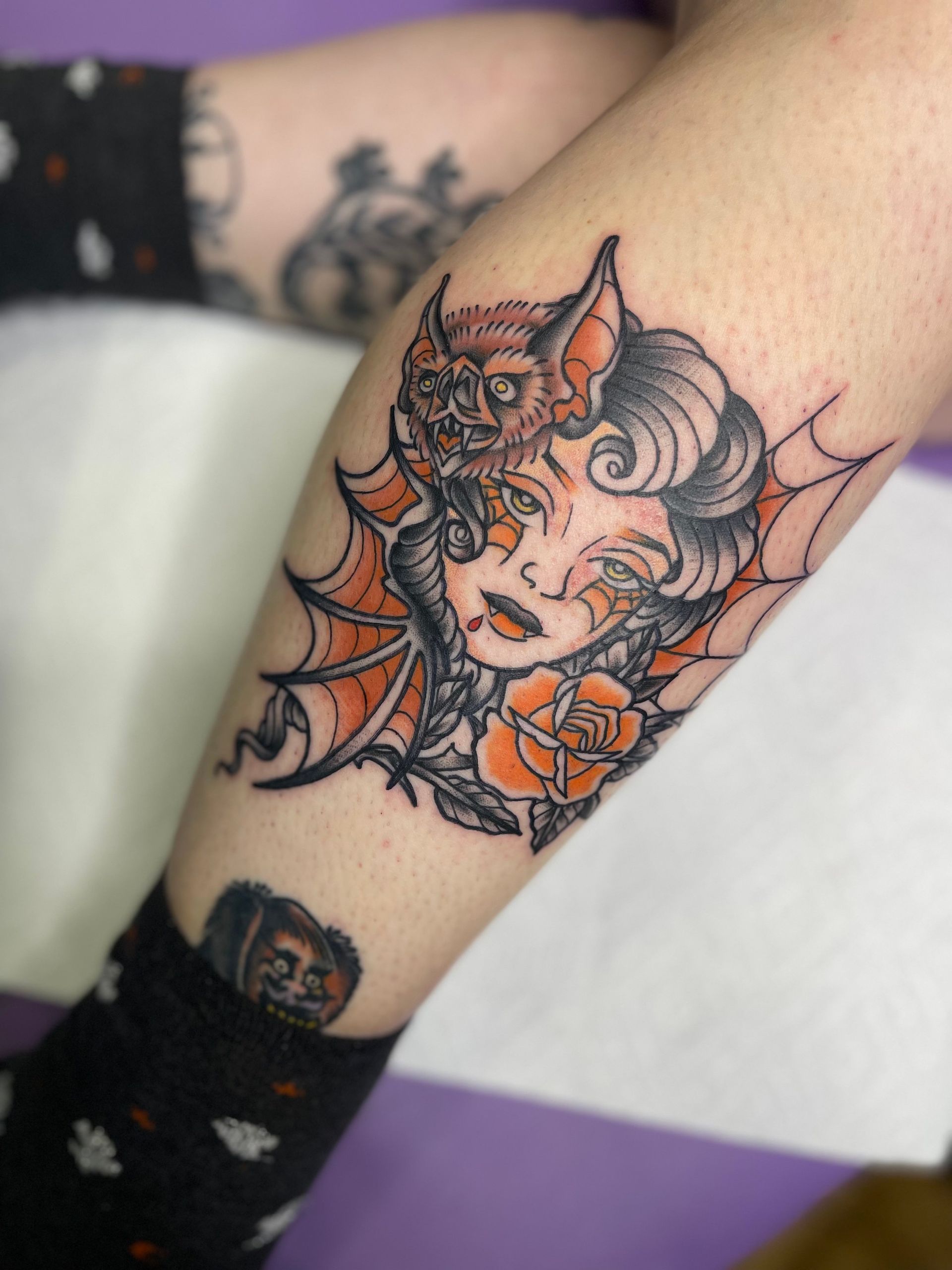 A woman has a tattoo of a bat on her leg