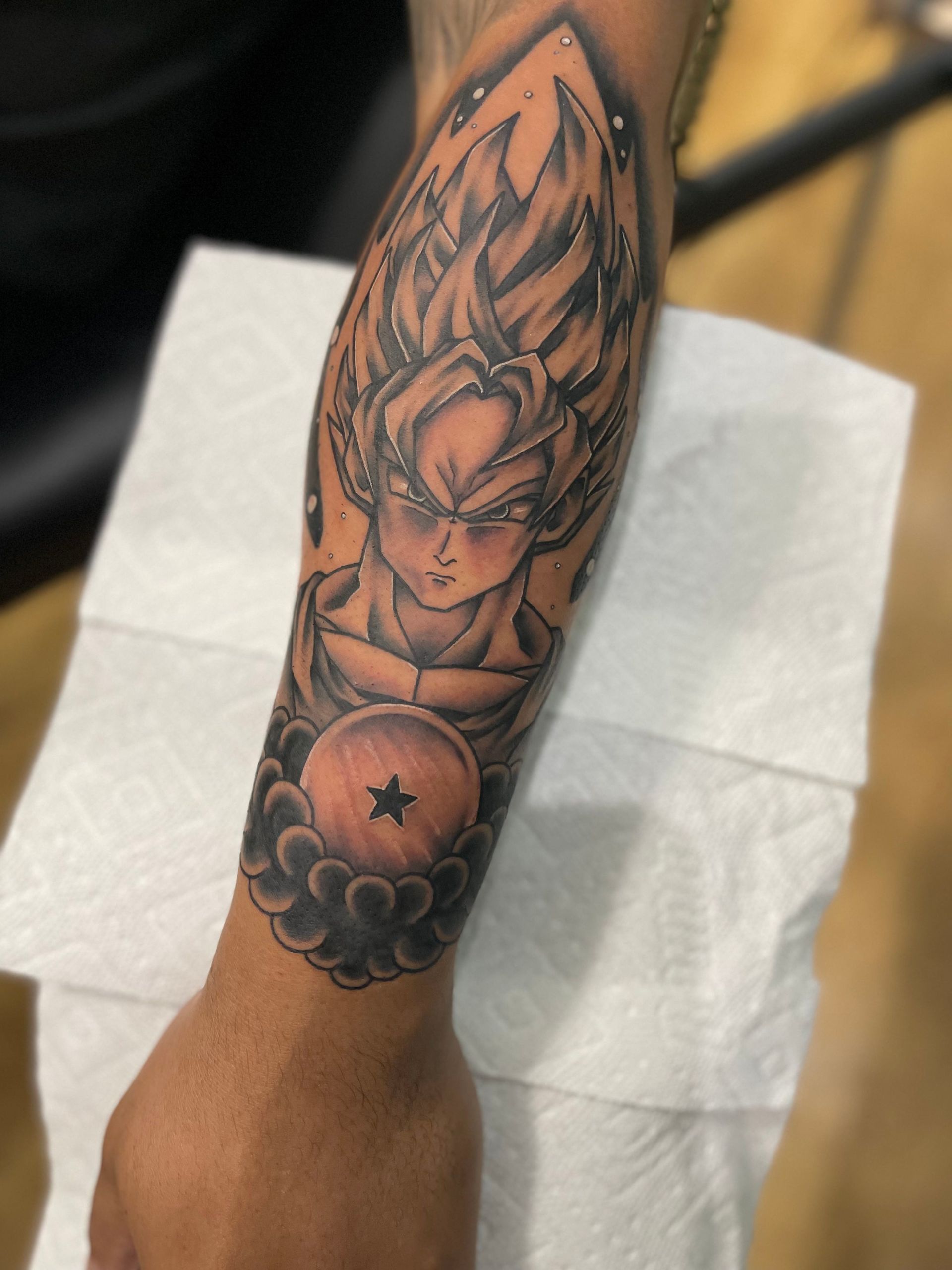 A man has a tattoo of Goku on his forearm
