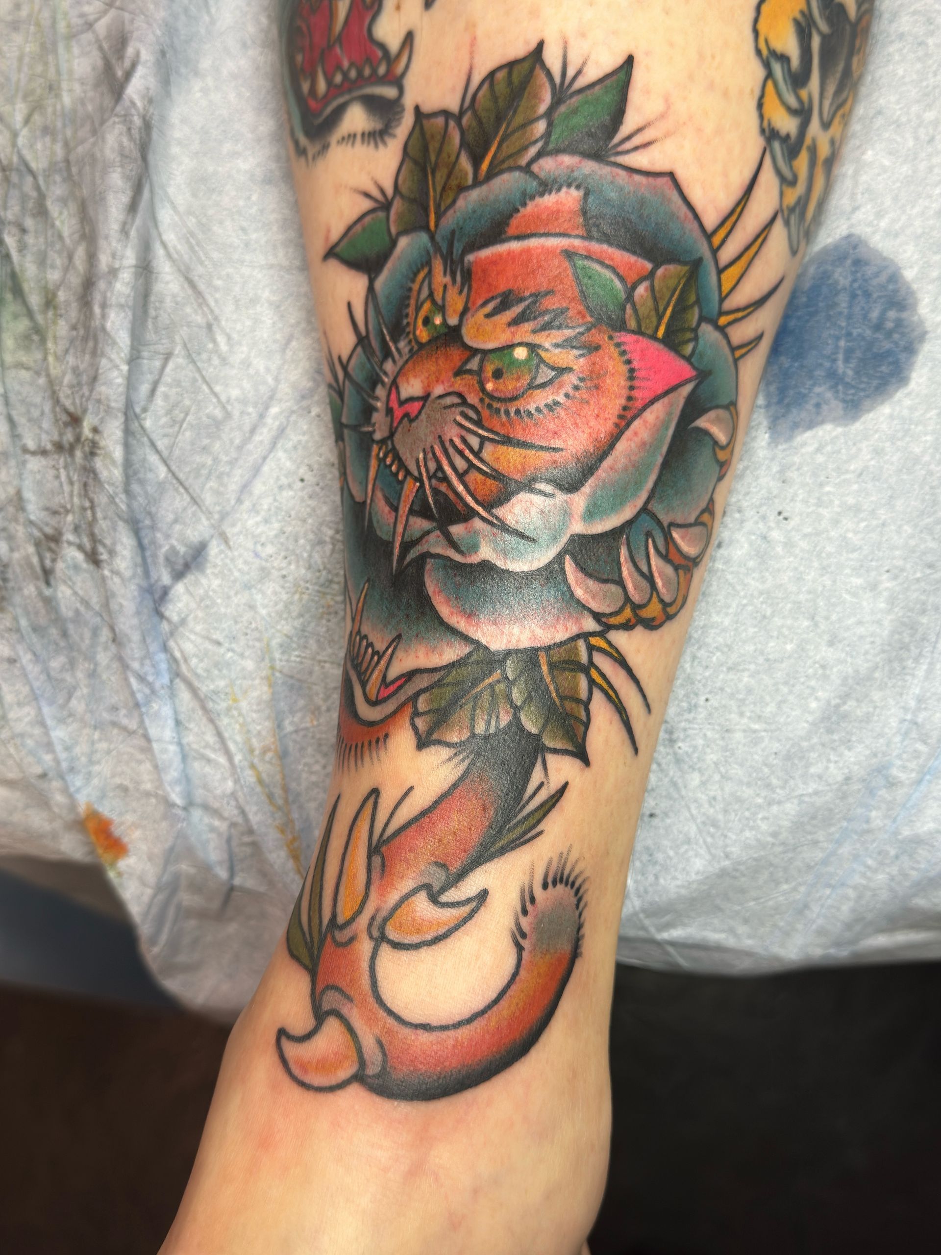 A person has a tattoo of a cat and a rose on their arm