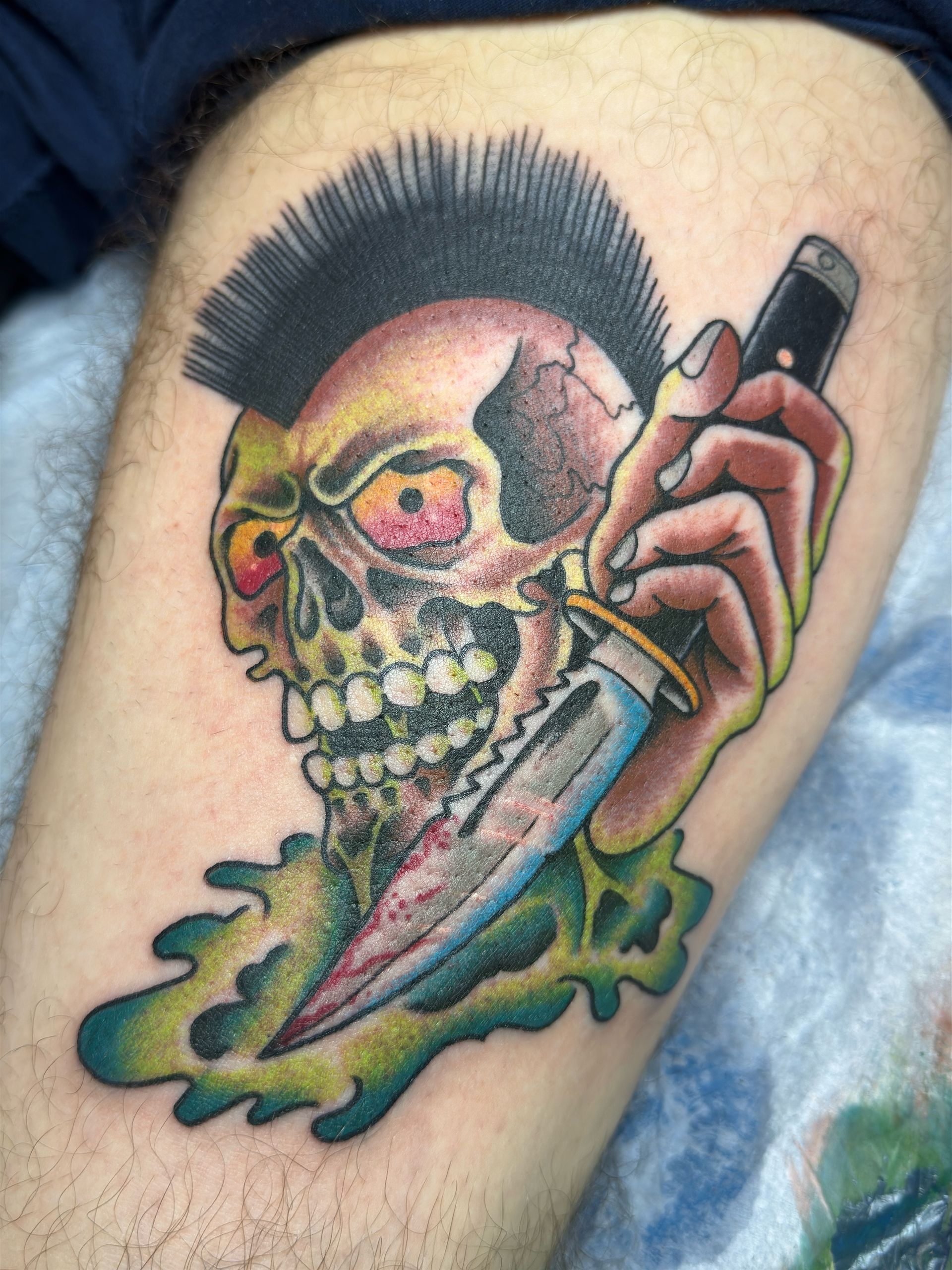 A tattoo of a skull holding a knife