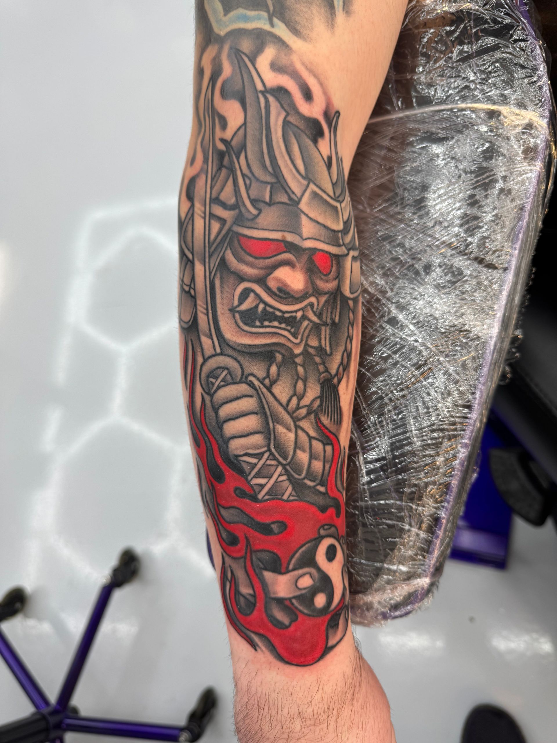 A man has a tattoo of a samurai on his forearm