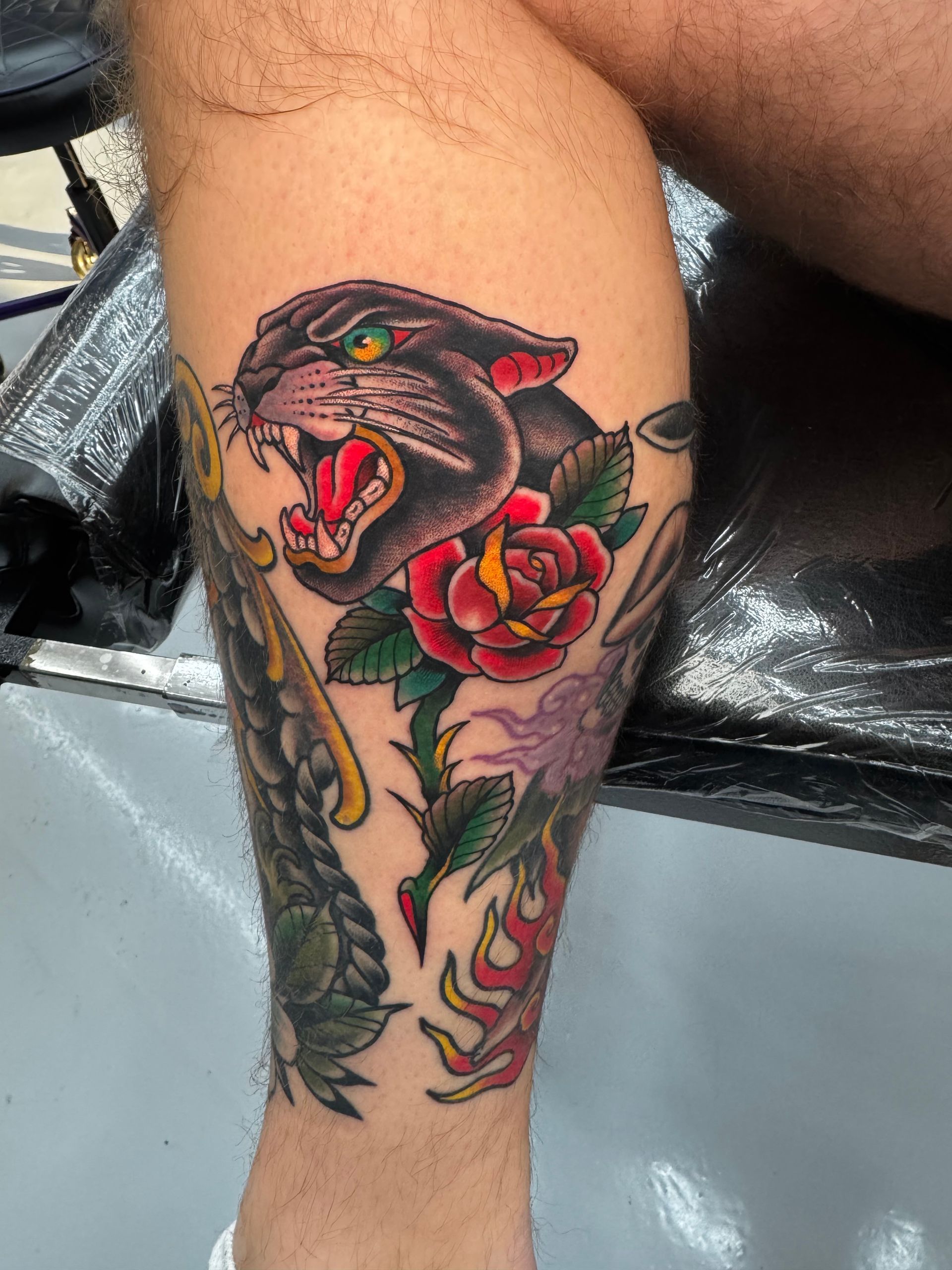 A man has a tattoo of a panther and roses on his leg