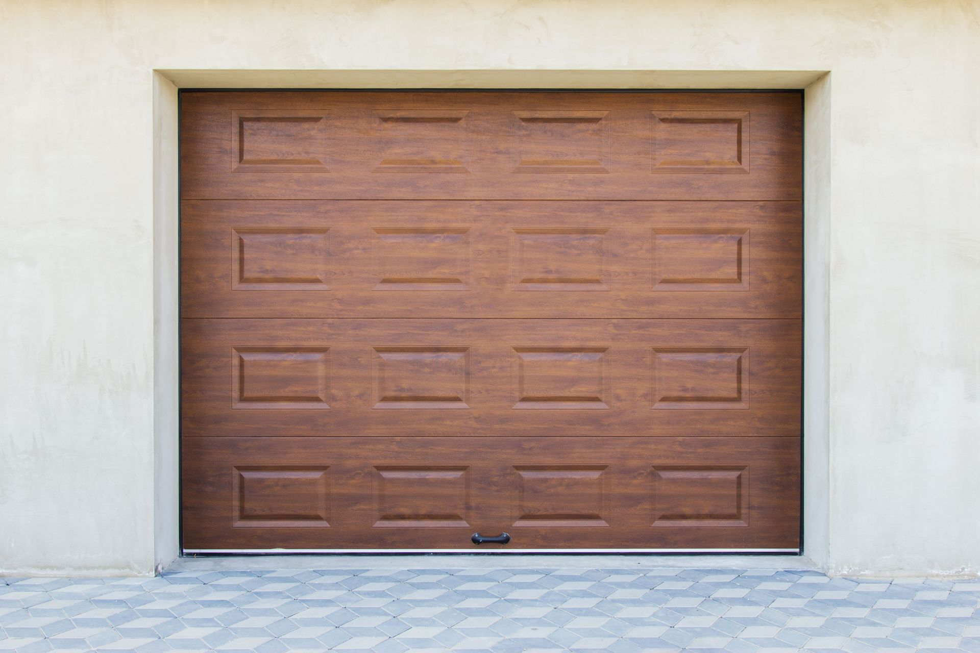 Brown garage door, textured wood-grain, with square panel design, set in a light-colored concrete opening.