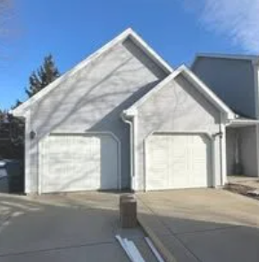 Black garage door with horizontal windows in a concrete driveway.