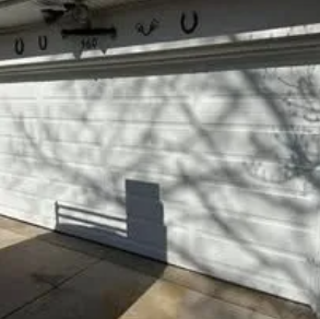 Dark blue two-car garage with black garage doors and a small rectangular window above.