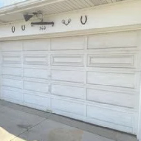 A garage with three brown doors, brick facade, and a work van parked in the driveway.