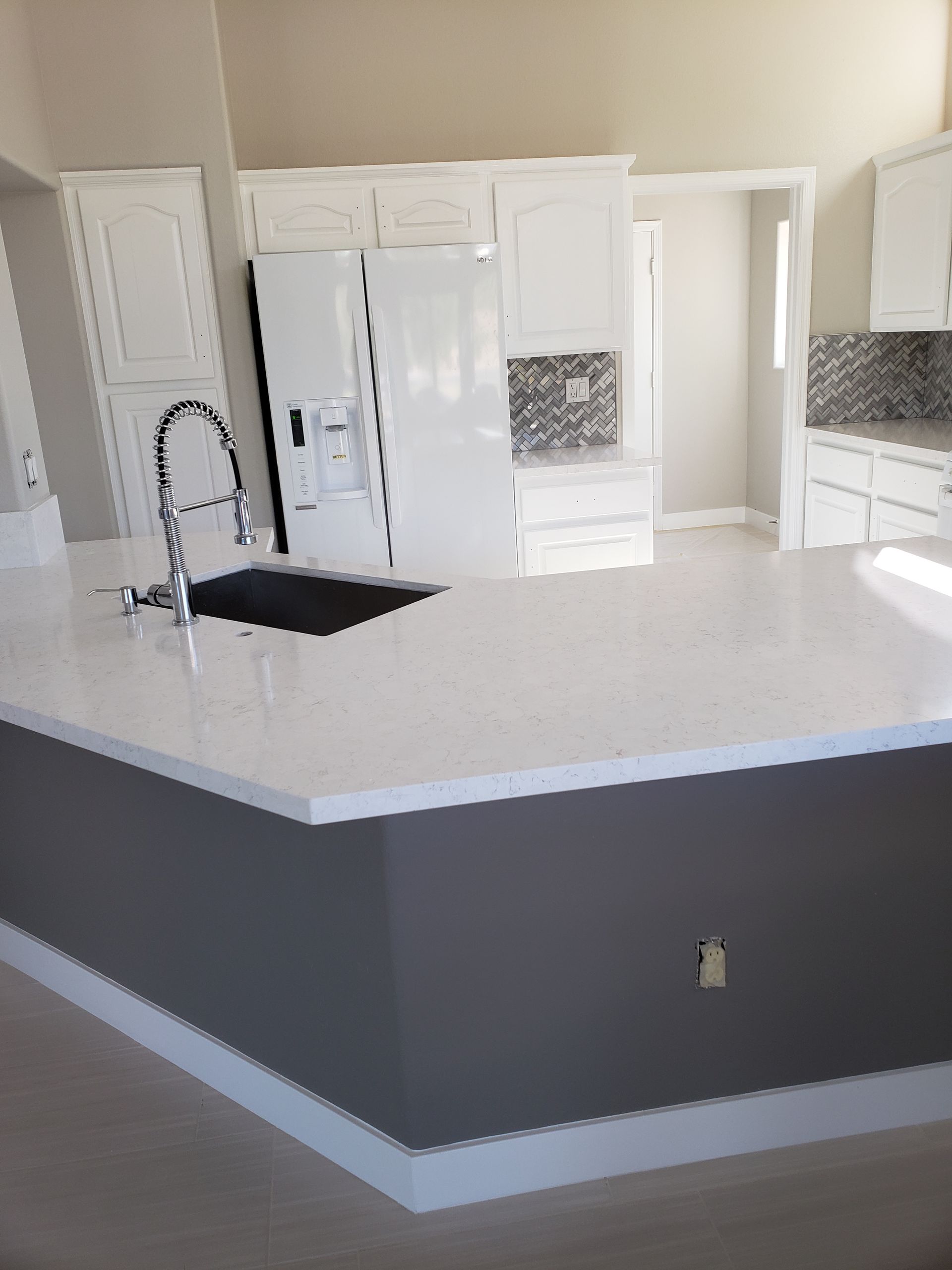 A kitchen with white cabinets , a sink , and a refrigerator.