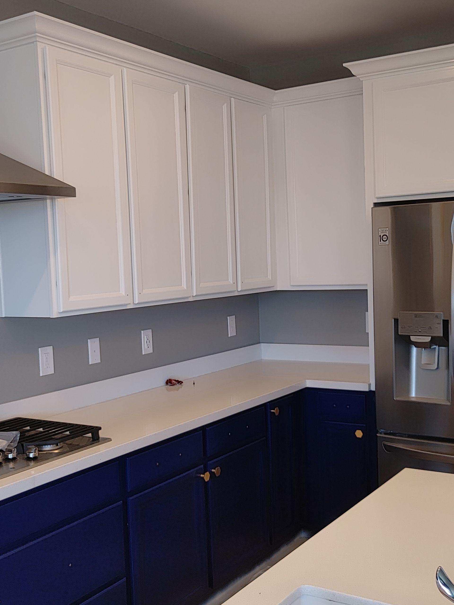 A kitchen with blue cabinets and white cabinets and a stainless steel refrigerator