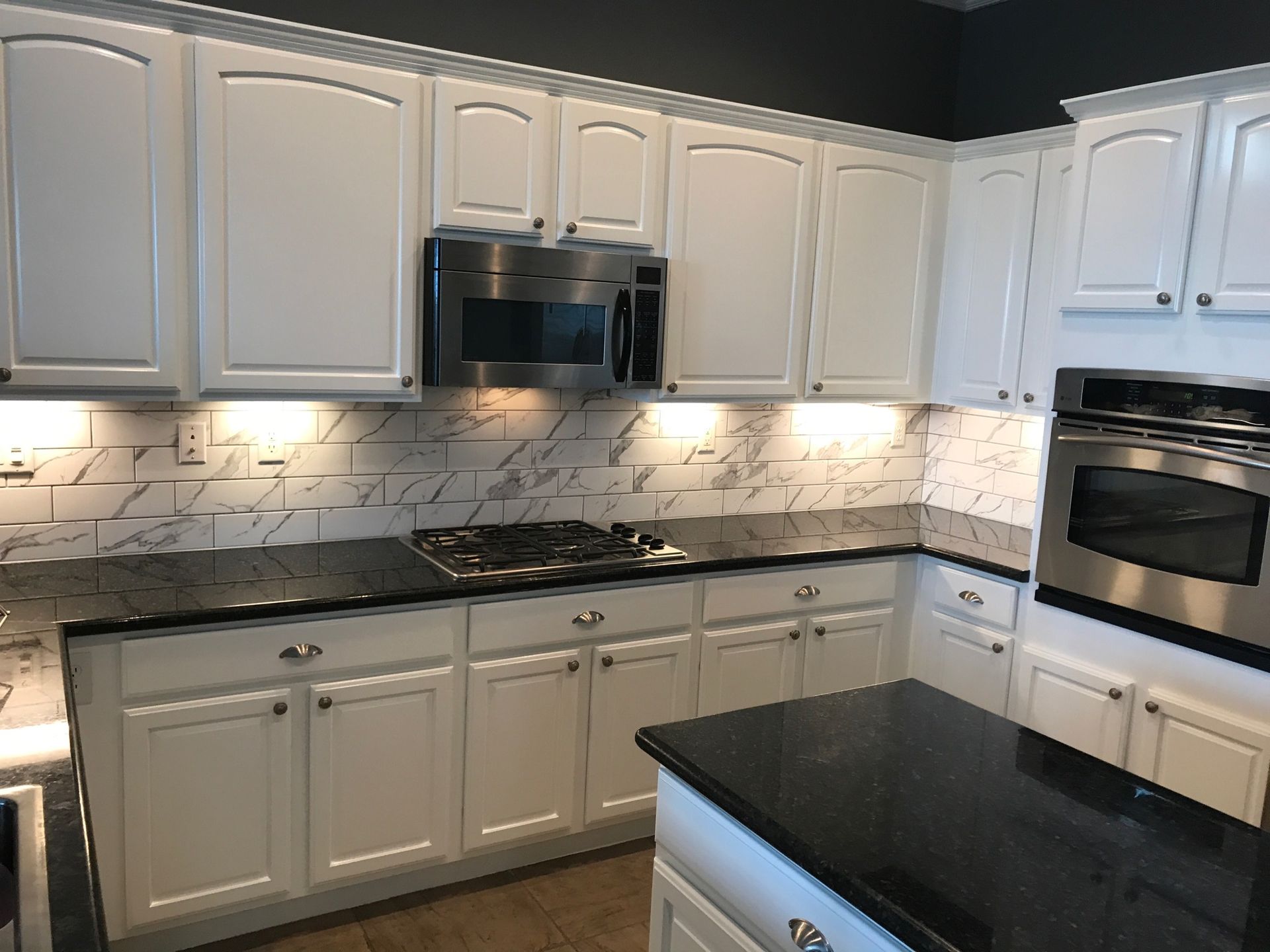 A kitchen with white cabinets and stainless steel appliances