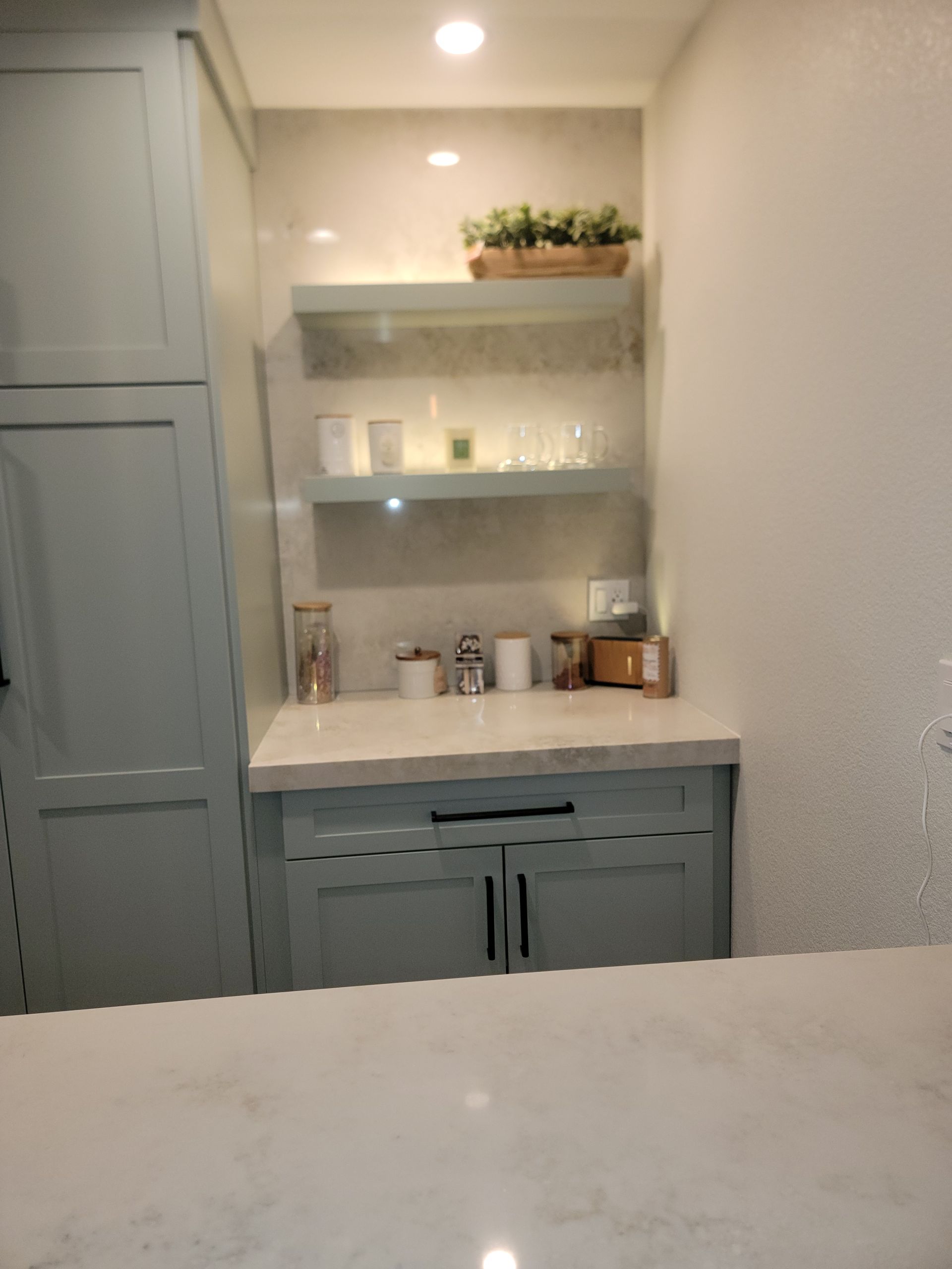 A built-in kitchen nook with shelves, cabinets, and countertop in pale blue and white.