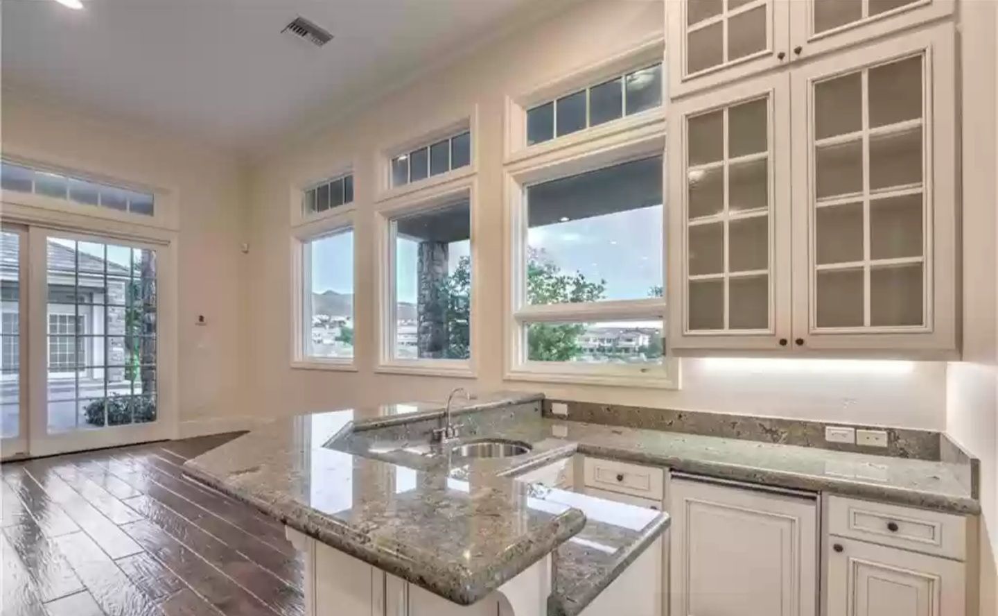 Kitchen with white cabinets, granite countertop, and large windows overlooking the outdoors.