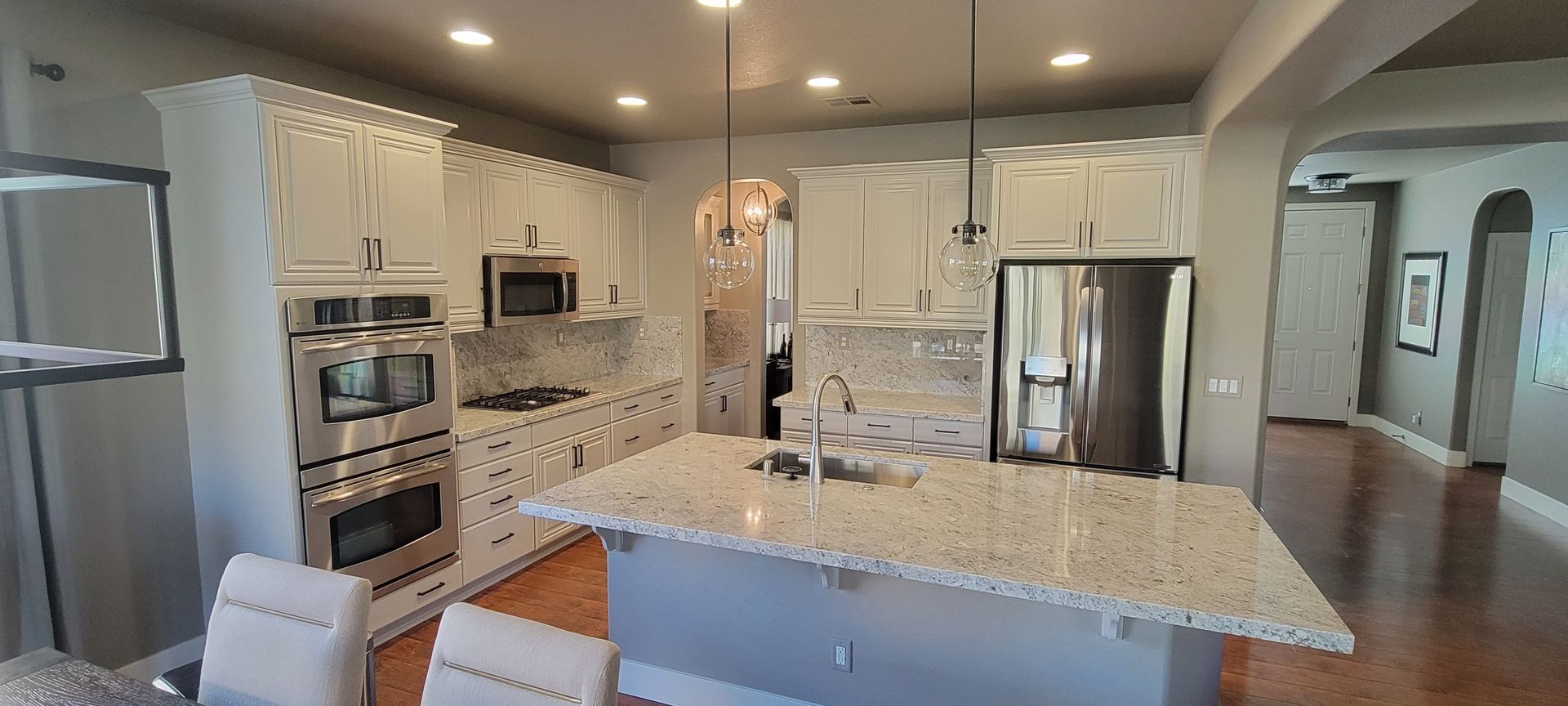 Kitchen with white cabinets, stainless steel appliances, granite countertops, and an island.