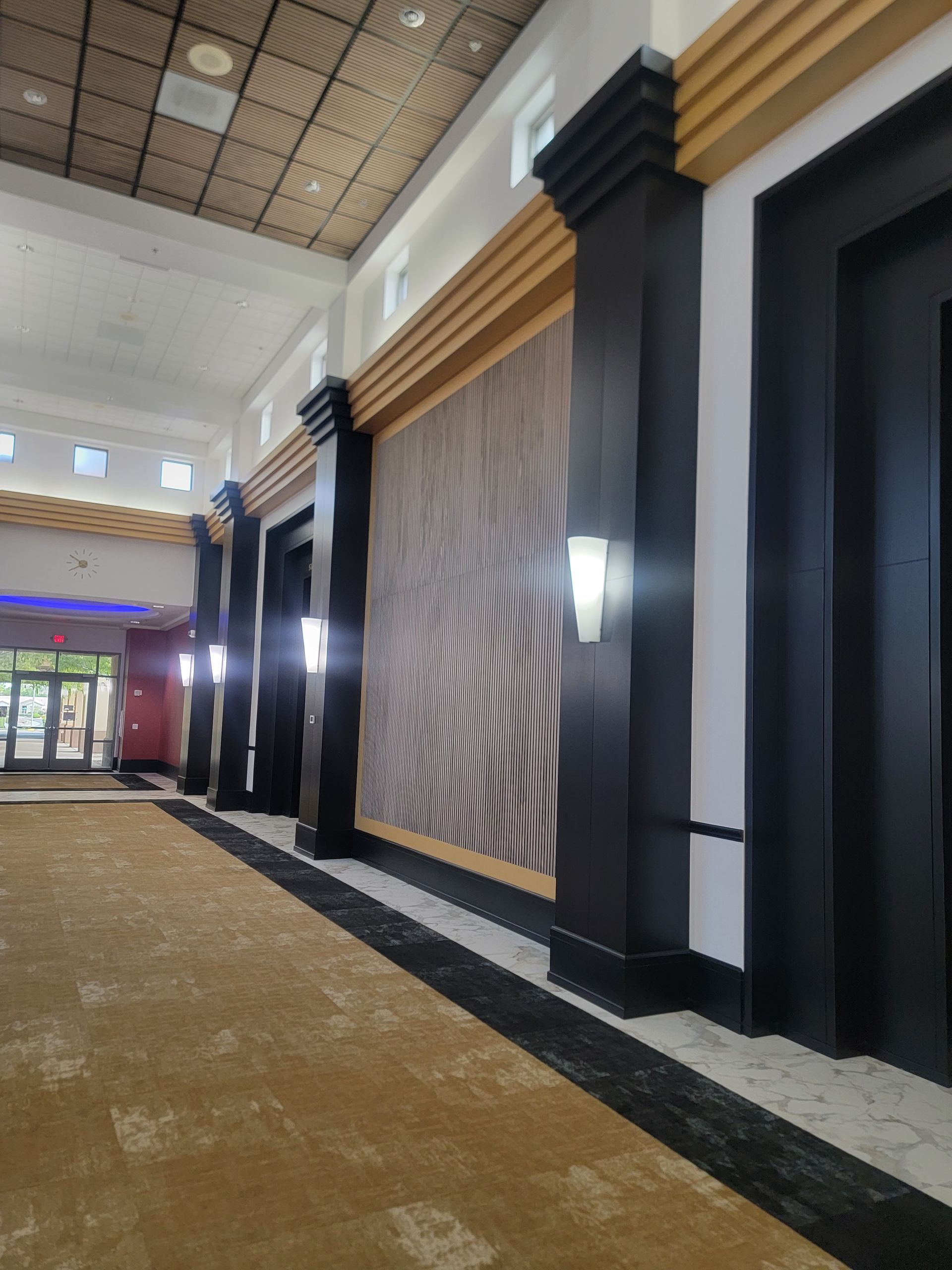 Hallway with columns, decorative wall, and textured carpet.
