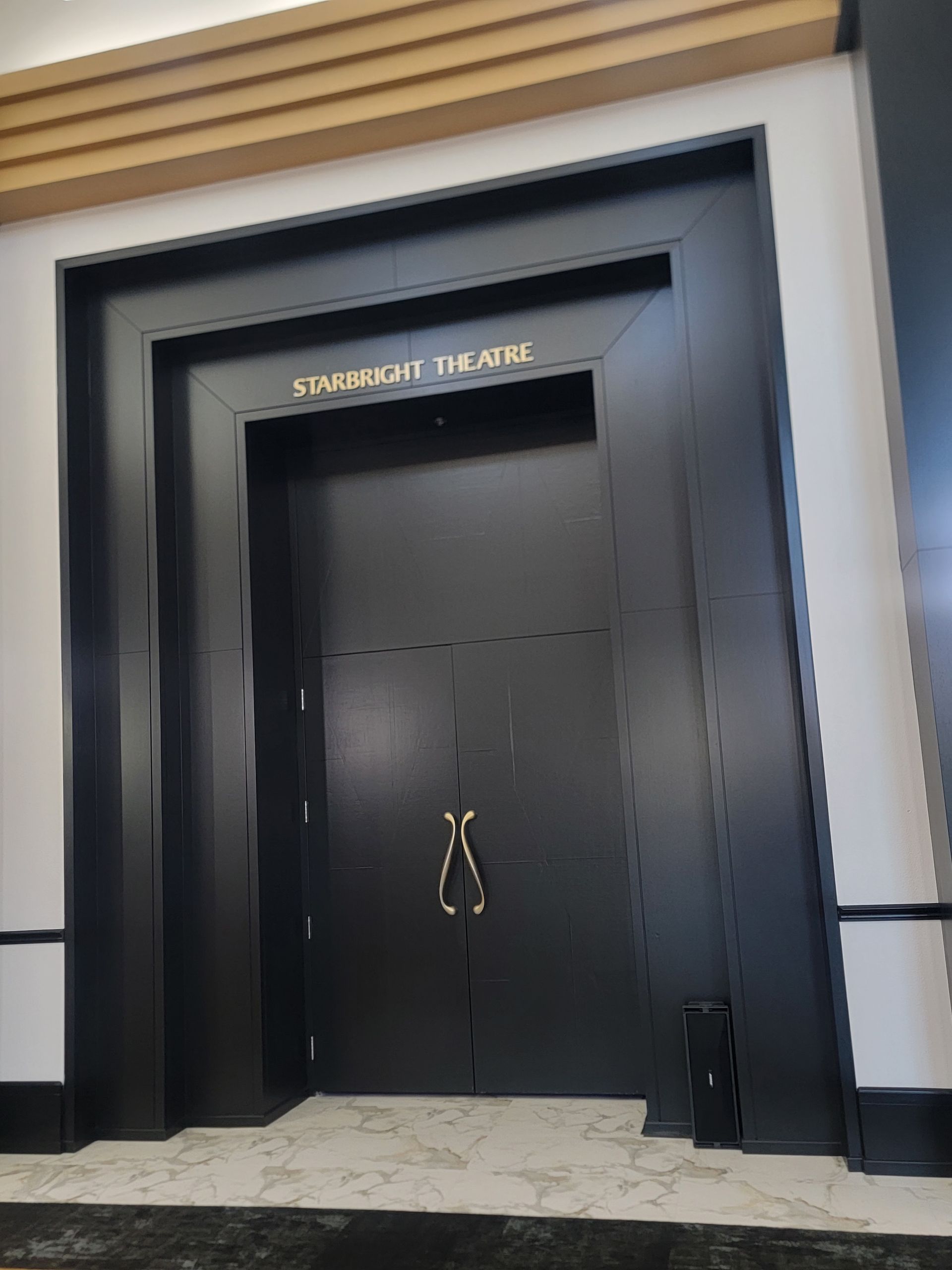 Black double doors with gold handles and the inscription
