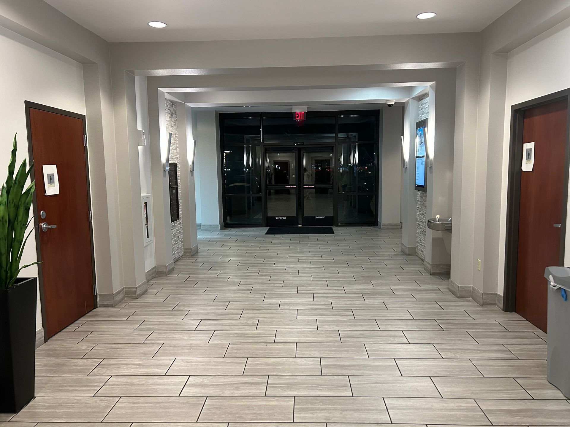 Hallway with tile floor, doors, and entrance with glass doors.