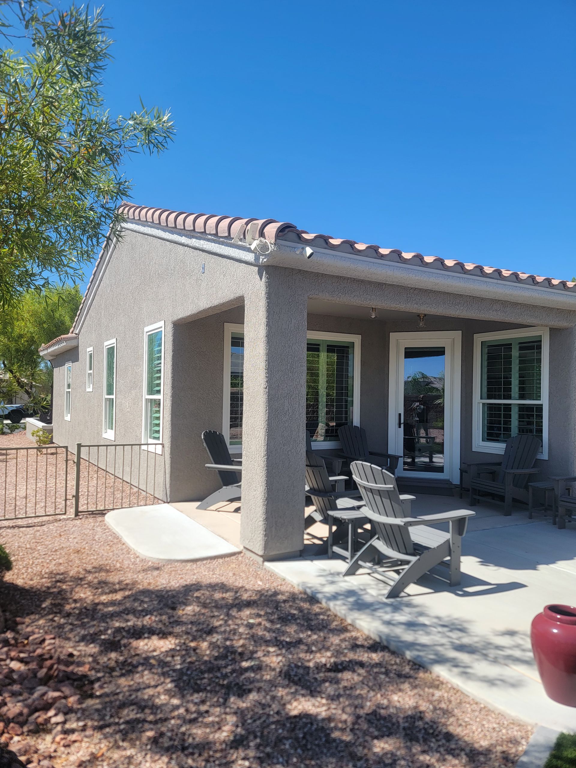 Patio of a stucco house with seating, under a terracotta-tiled roof.