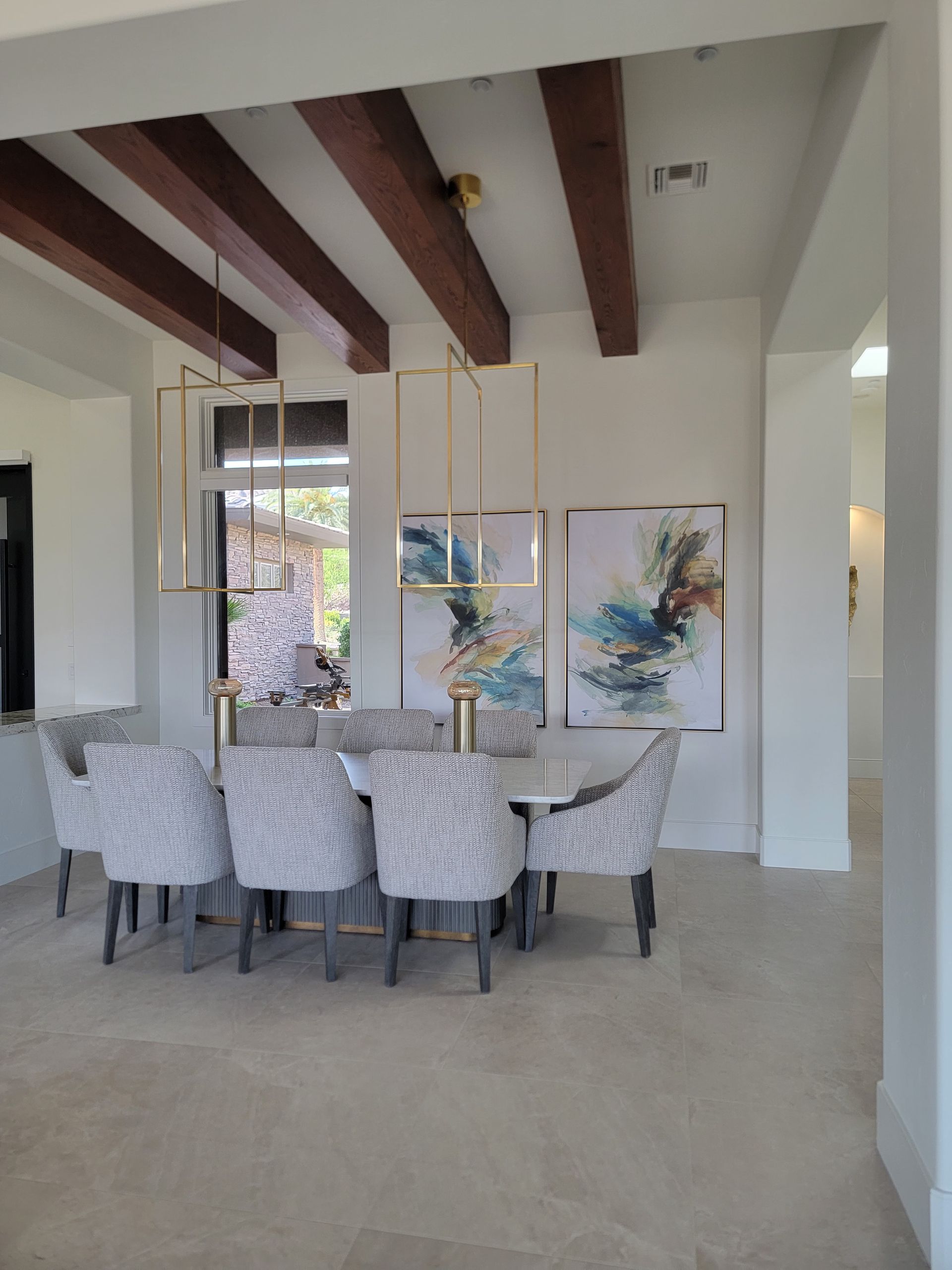Elegant dining room with table, chairs, artwork, and exposed ceiling beams.