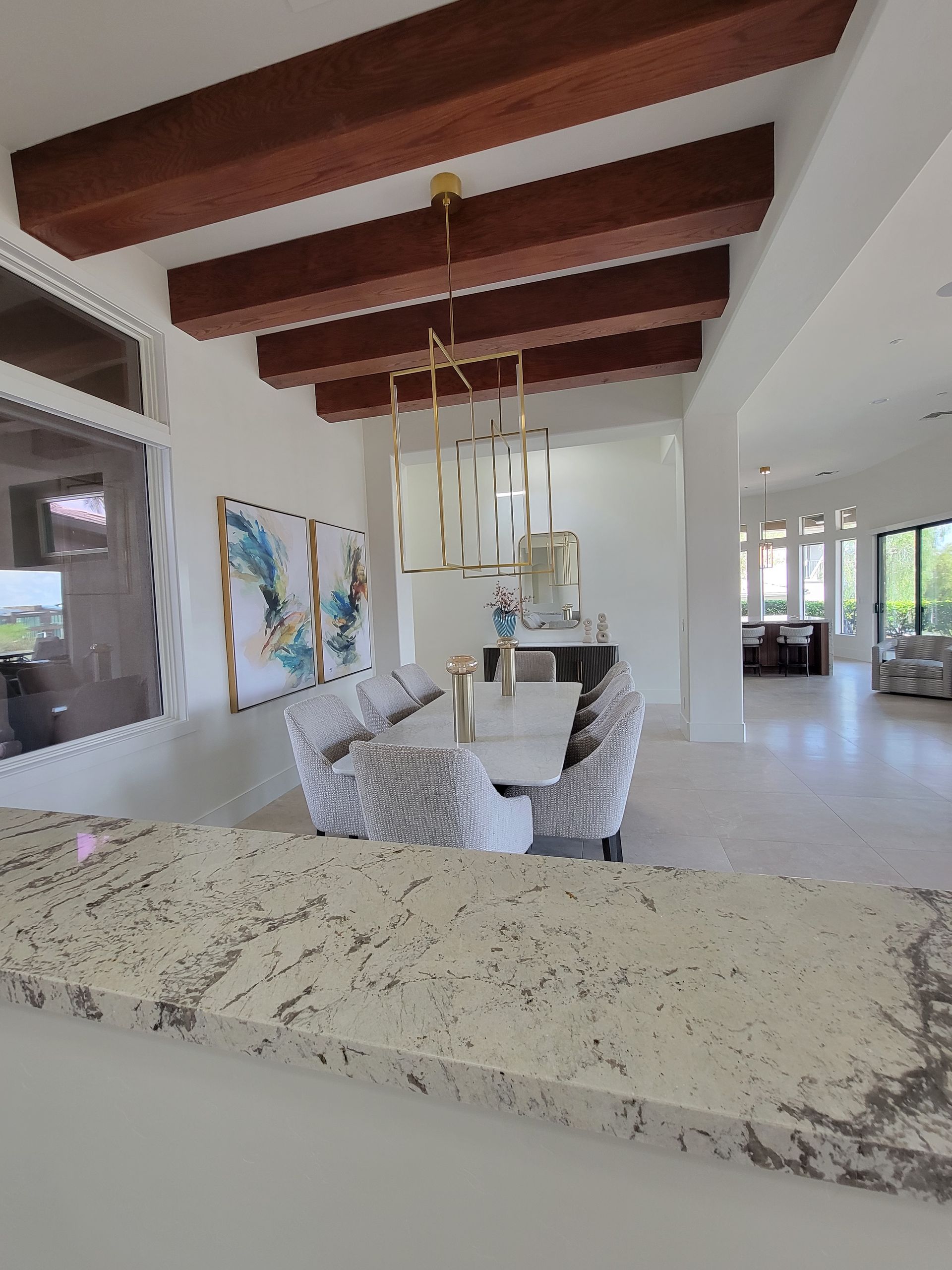 Interior view: dining room with white walls, exposed wood beams, and a modern chandelier.
