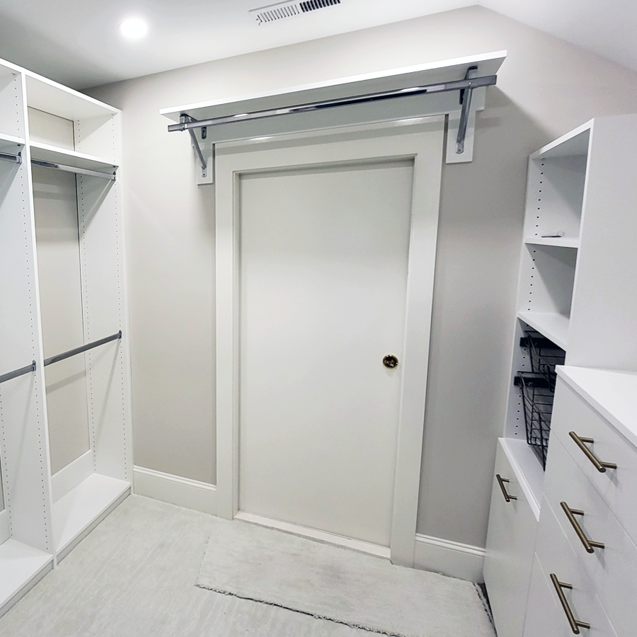 White closet with door, built-in shelving, and hanging bar.