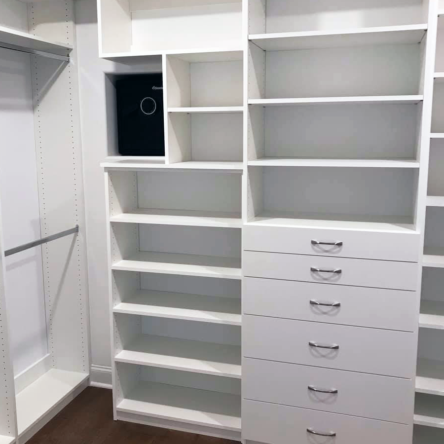 White custom closet with shelves, drawers, and a built-in safe.