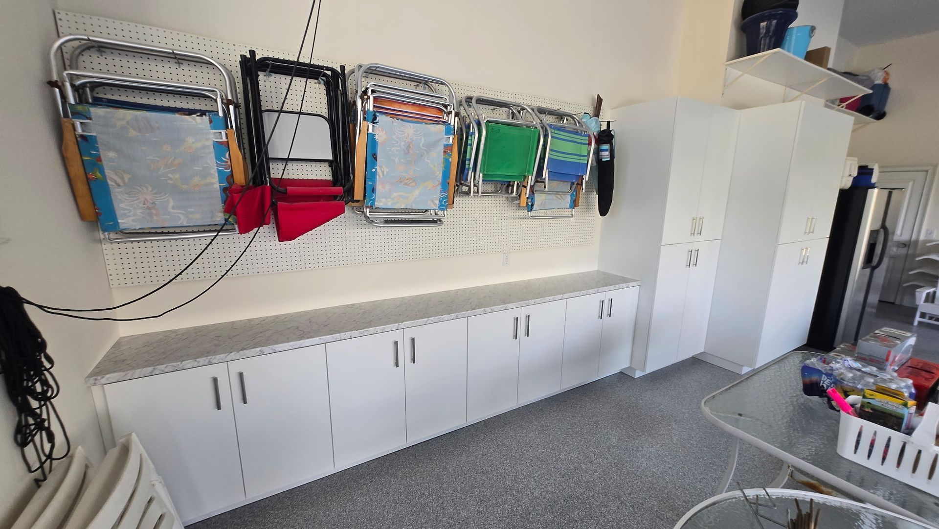 Classroom wall with hanging backpacks, long white storage cabinets, and a white cabinet by a window