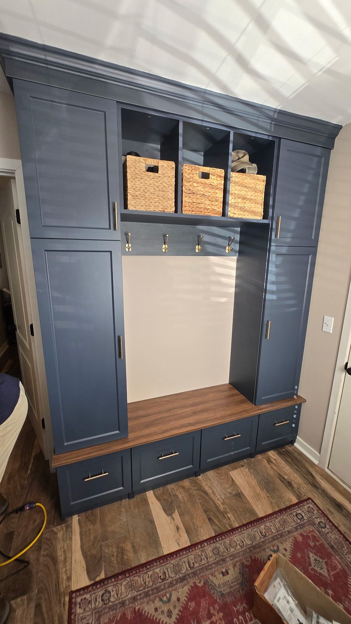 Blue built-in cabinet with open center, wicker baskets on top, and drawers at the bottom in a room