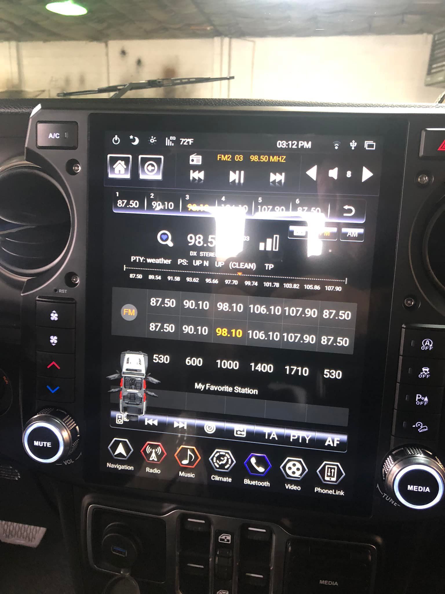 Large touchscreen car infotainment system displaying radio controls, with surrounding buttons and dials.