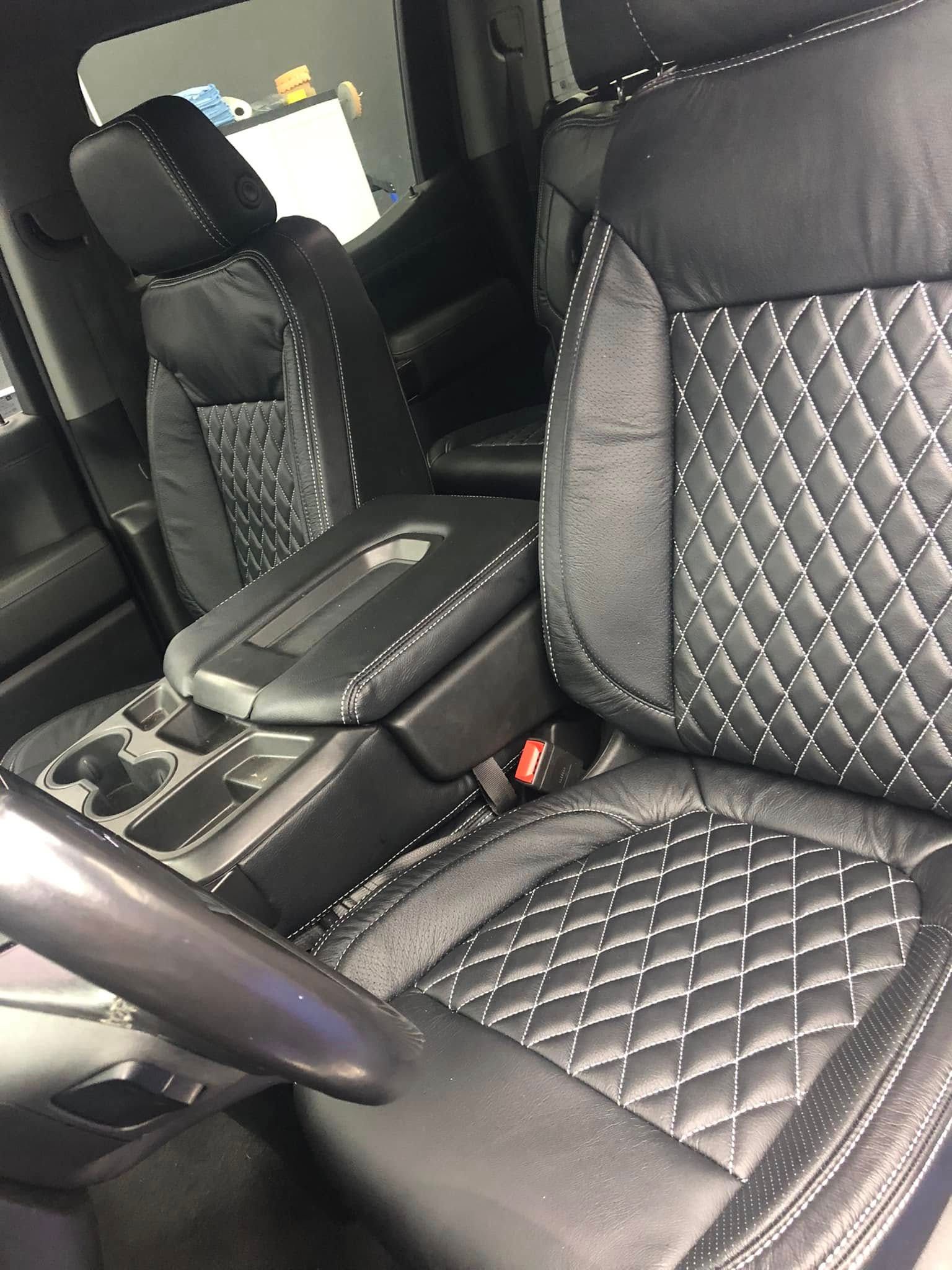 Black leather car seats with diamond stitching in a vehicle's interior.