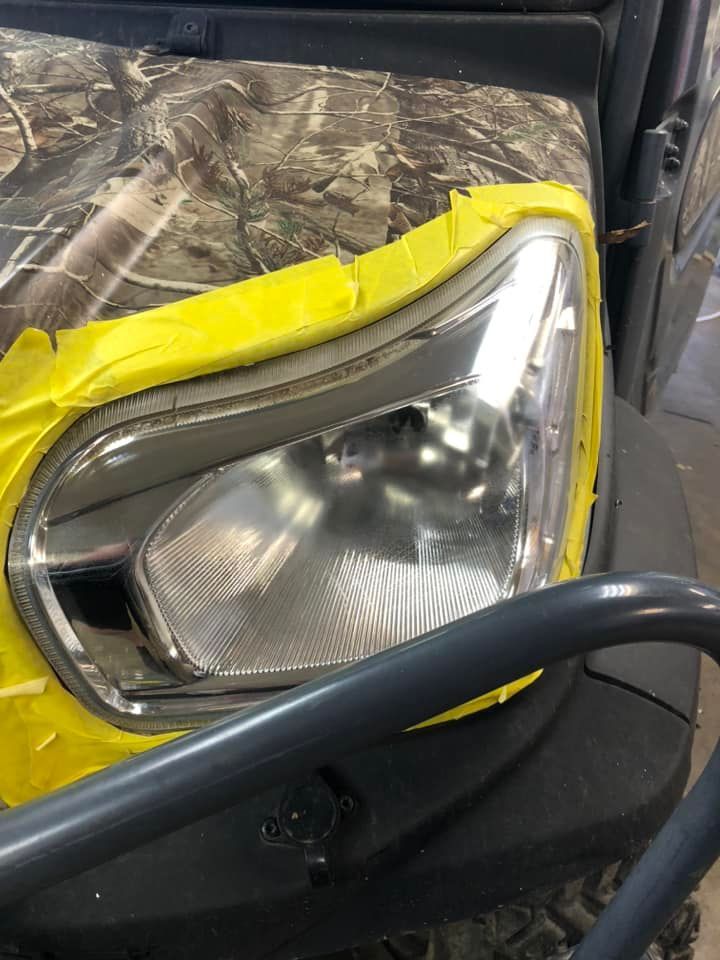Headlight of vehicle taped with yellow masking tape, camouflage hood.
