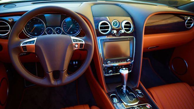Luxury car interior with brown leather seats, steering wheel, dashboard, and center console view