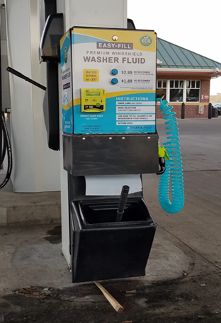 A washer fluid dispenser at a gas station with a hose attached to it.