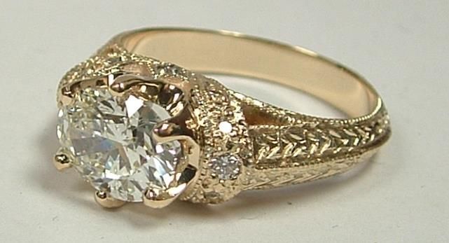 Gold engagement ring with a large, round diamond and intricate details.