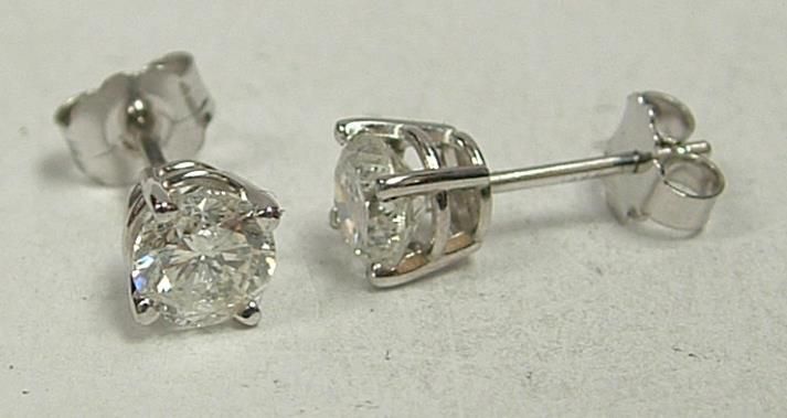 Diamond stud earrings with silver posts and backs on a white surface.