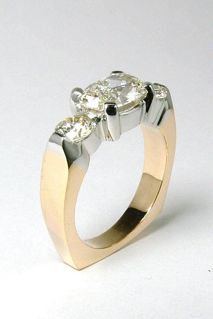Gold and white gold engagement ring with three clear diamonds set in a modern design.