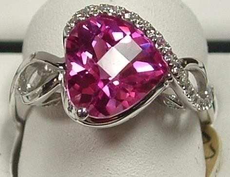 A heart-shaped pink gemstone ring with a halo of small diamonds and a silver band.