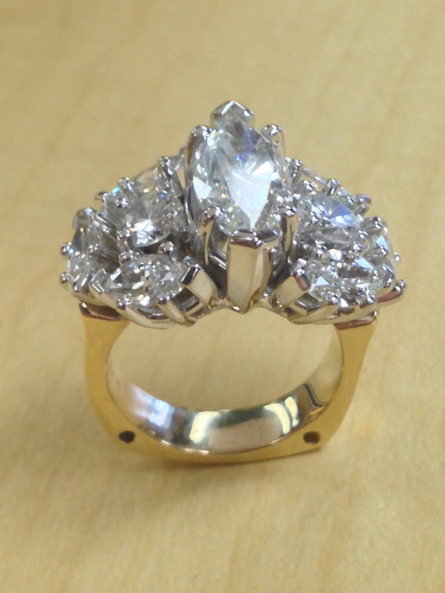 Diamond ring with a large marquise-cut center stone surrounded by smaller diamonds, set in gold and platinum.