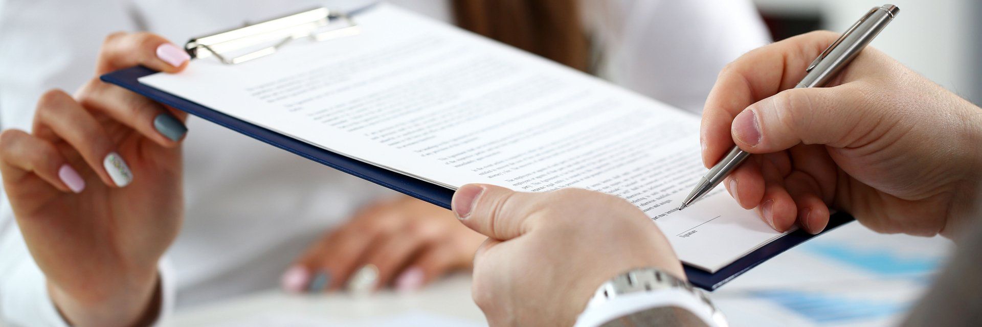 A person is writing on a clipboard with a pen.