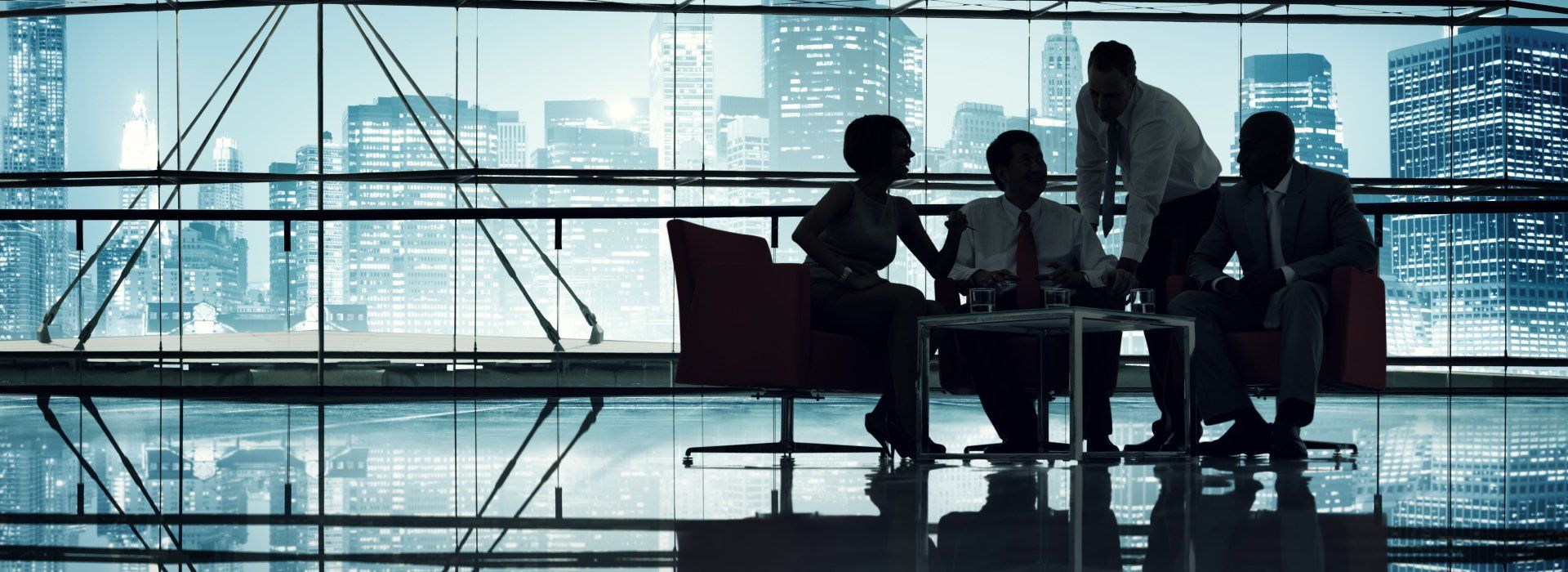 A group of business people are having a meeting in front of a large window.