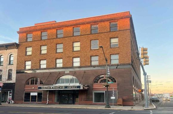 A large brick building is sitting on the corner of a city street.