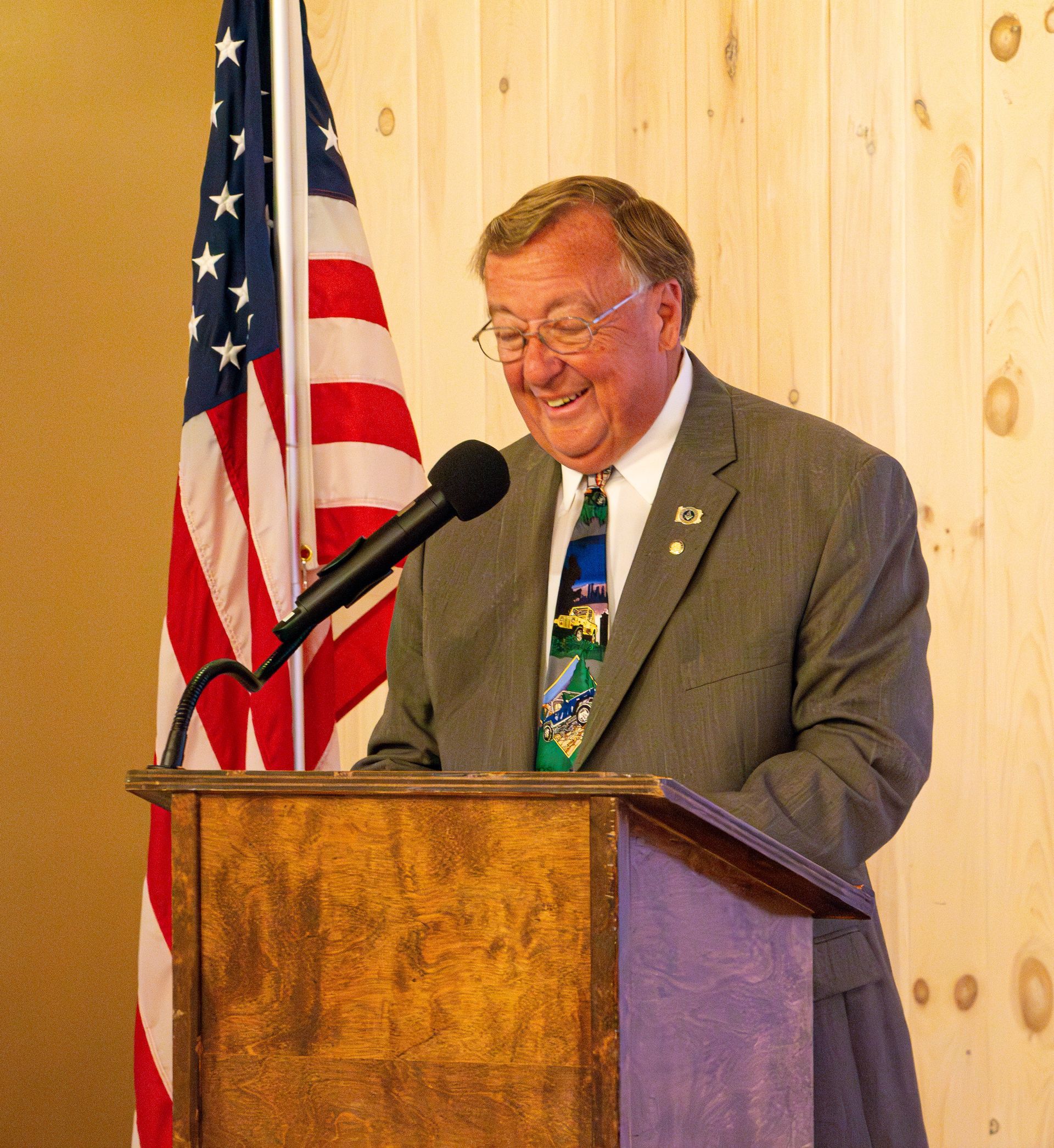 A man is giving a speech at a podium in front of an american flag