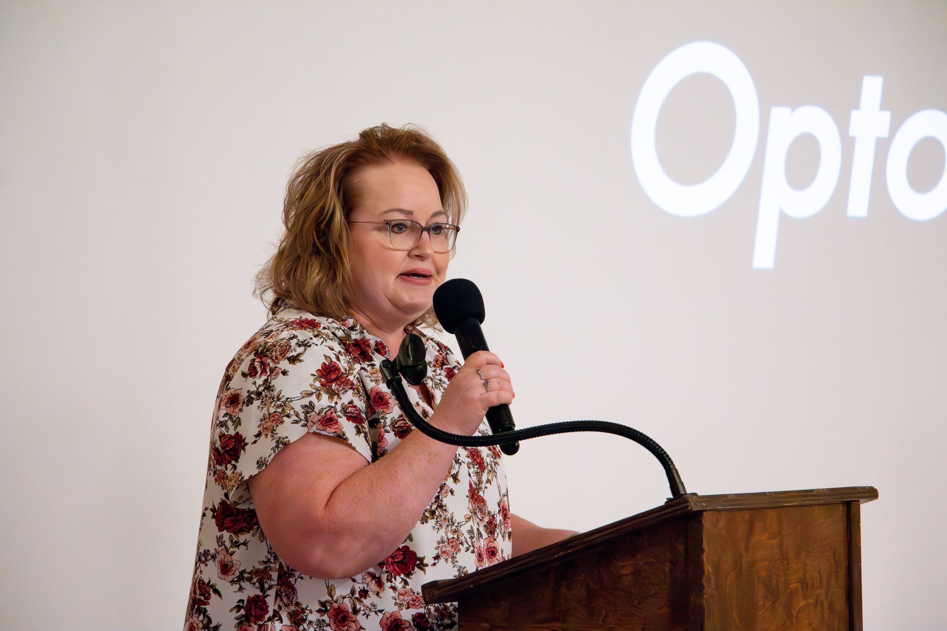 A woman is standing at a podium holding a microphone.