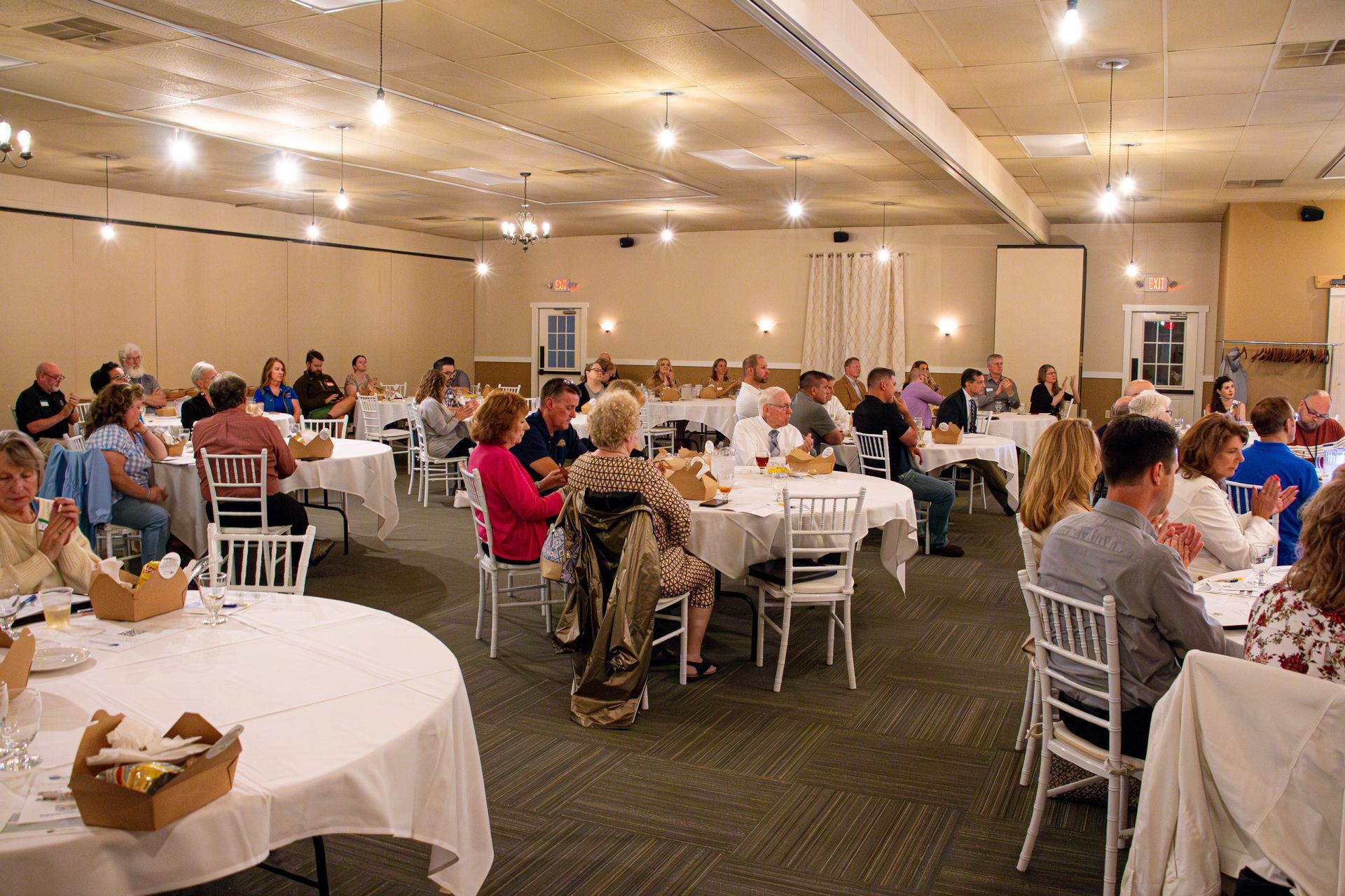 A large group of people are sitting at tables in a large room.