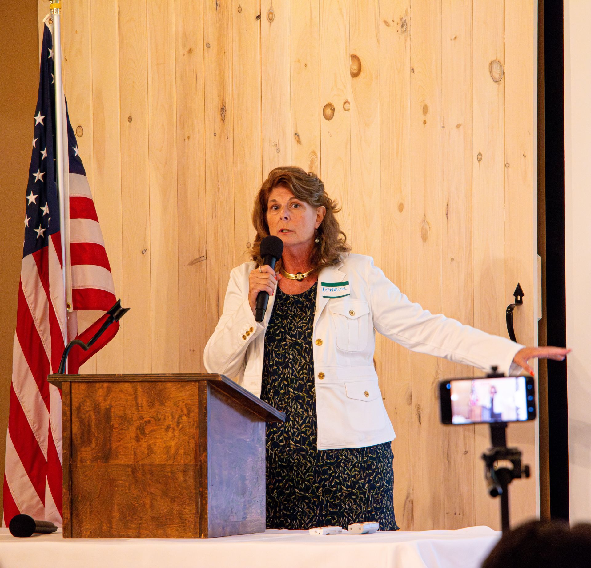 A woman stands at a podium speaking into a microphone