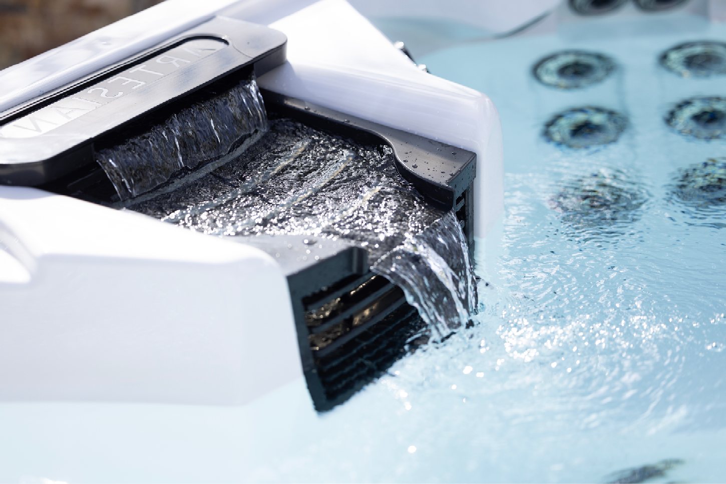 A waterfall is coming out of the side of a hot tub.