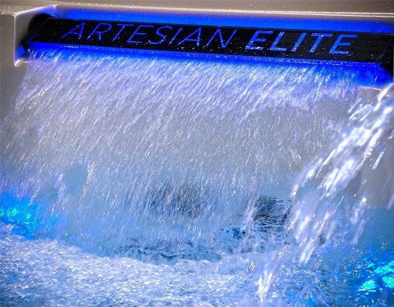 Artesian elite is written on the side of a waterfall