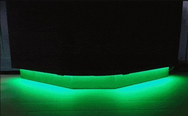 A green light is shining on a black surface.