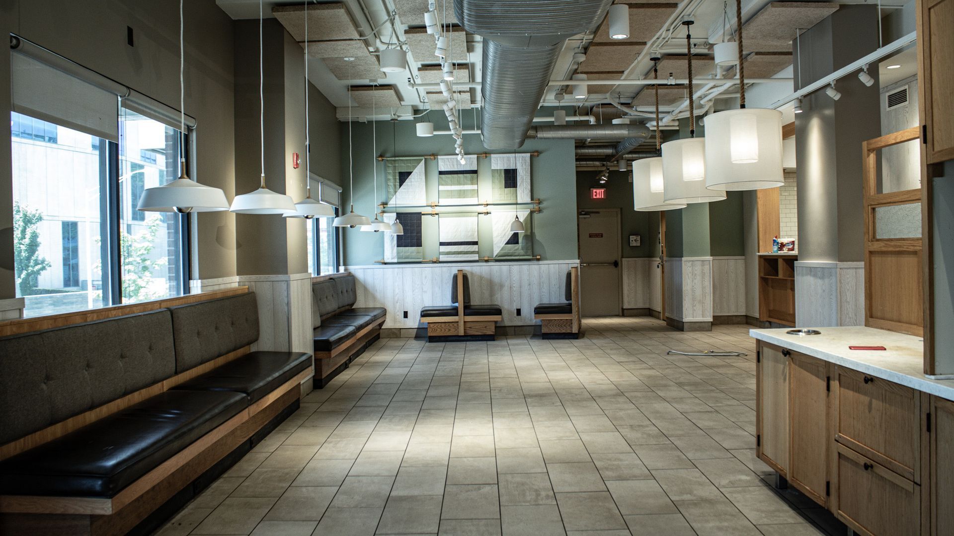Empty modern waiting room with benches, tiled floor, hanging pendant lights, and a reception counter