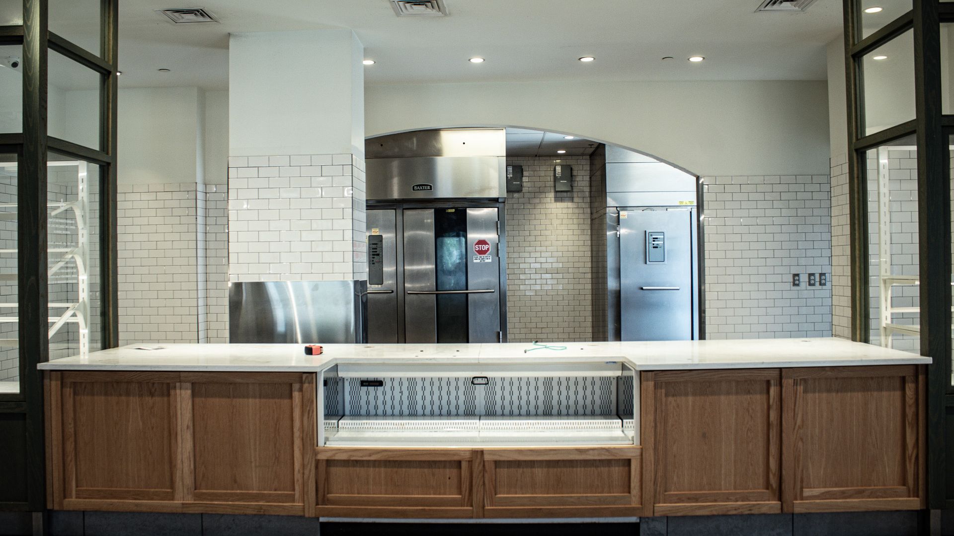Empty commercial kitchen counter with stainless steel ovens and tiled walls behind it